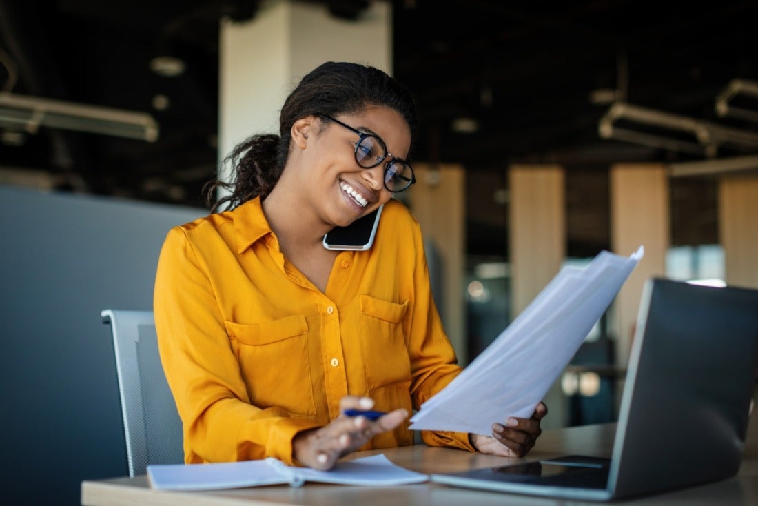 Professional Female Reviewing Data and Smiling on a Phone Call