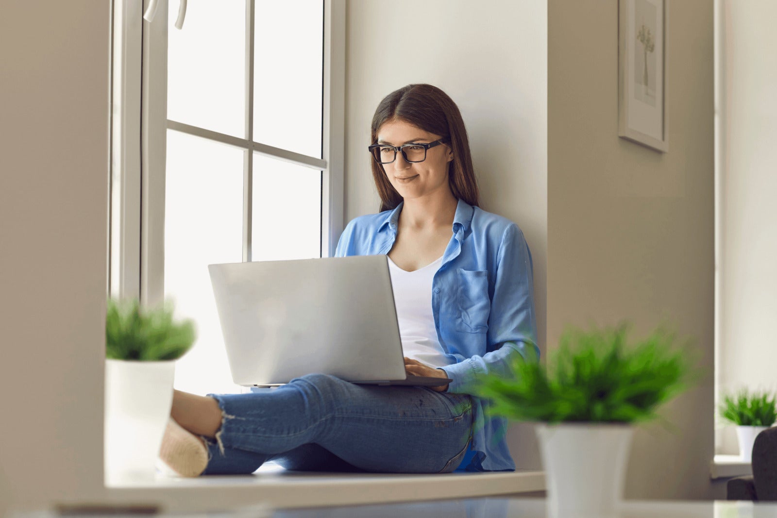 remote worker works on laptop while sitting leaning against wall