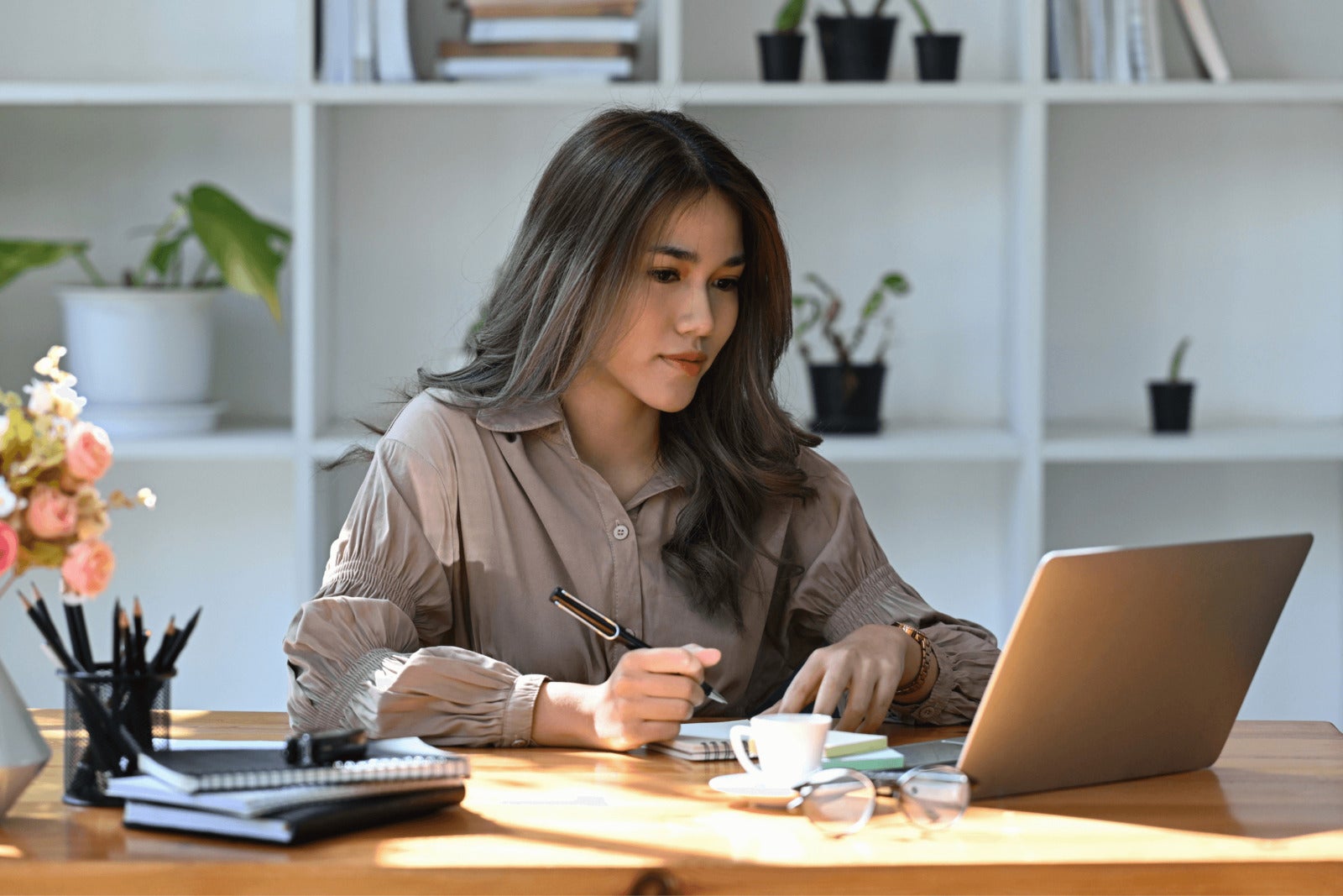 small business owner writes on notebook and works on laptop