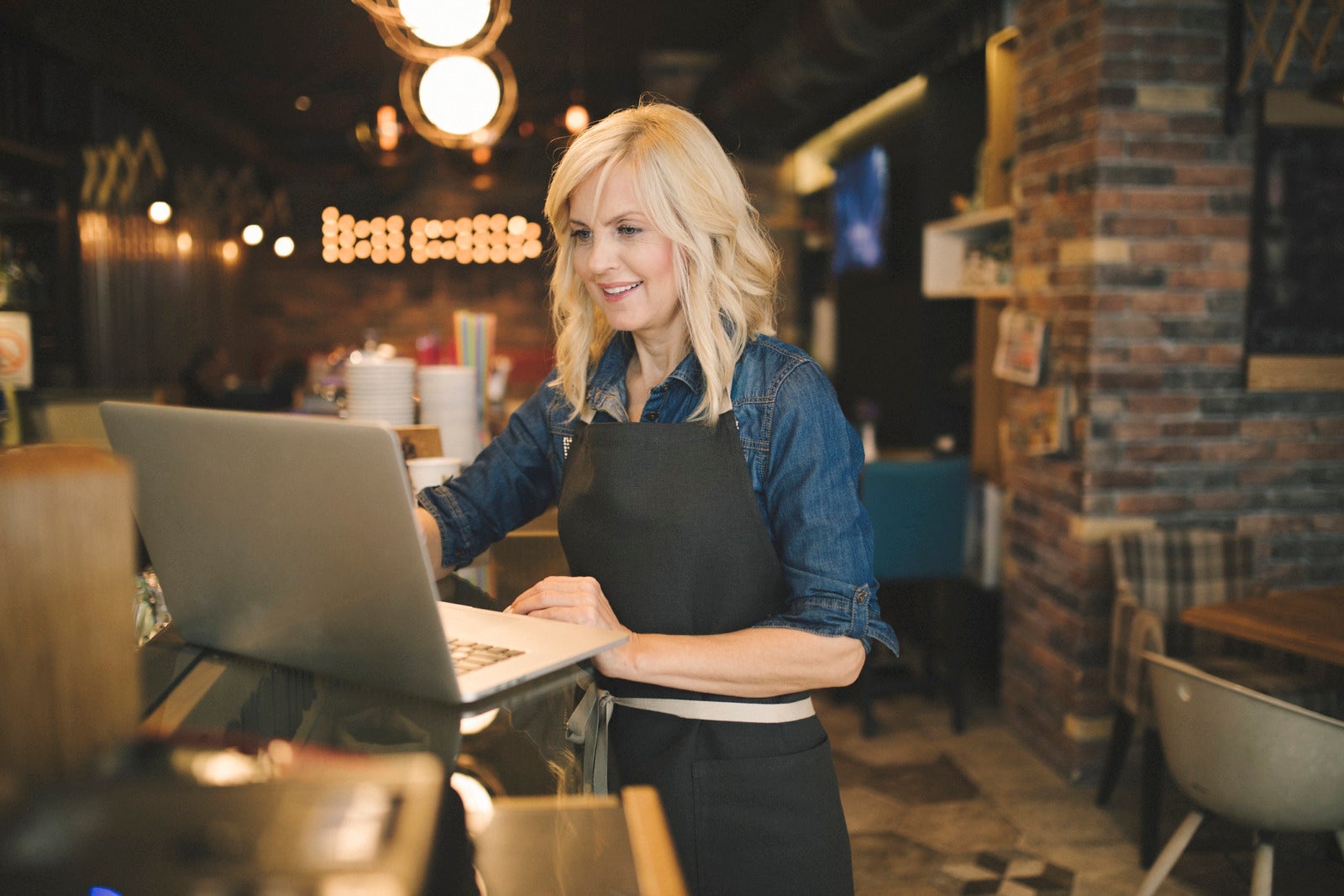 Coffee shop owner working on laptop small business recruiting