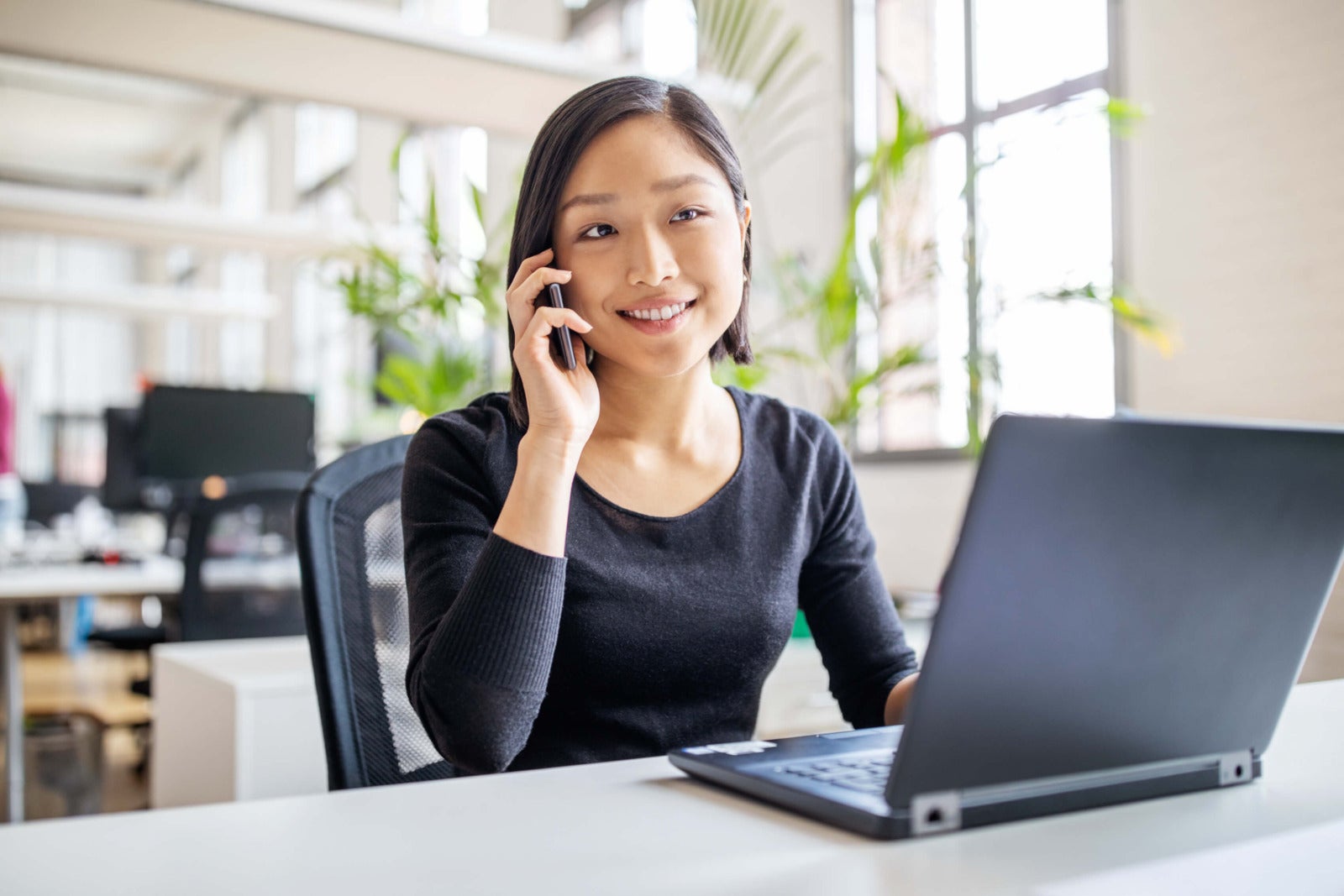 young business professional takes phone call while working on laptop
